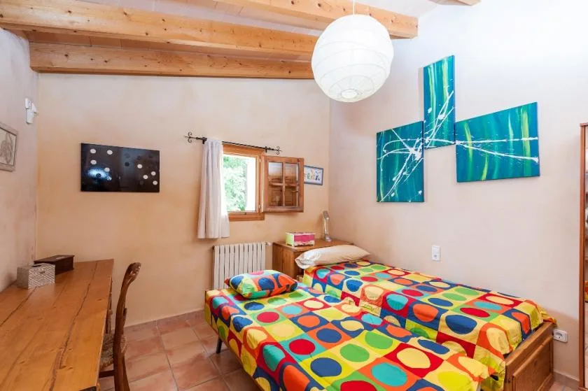 Un dormitorio con ropa de cama de colores y vigas de madera en el techo.