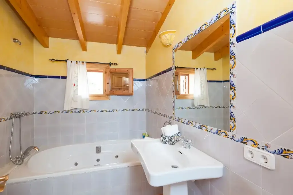 Un baño con bañera, lavabo y espejo de pared.