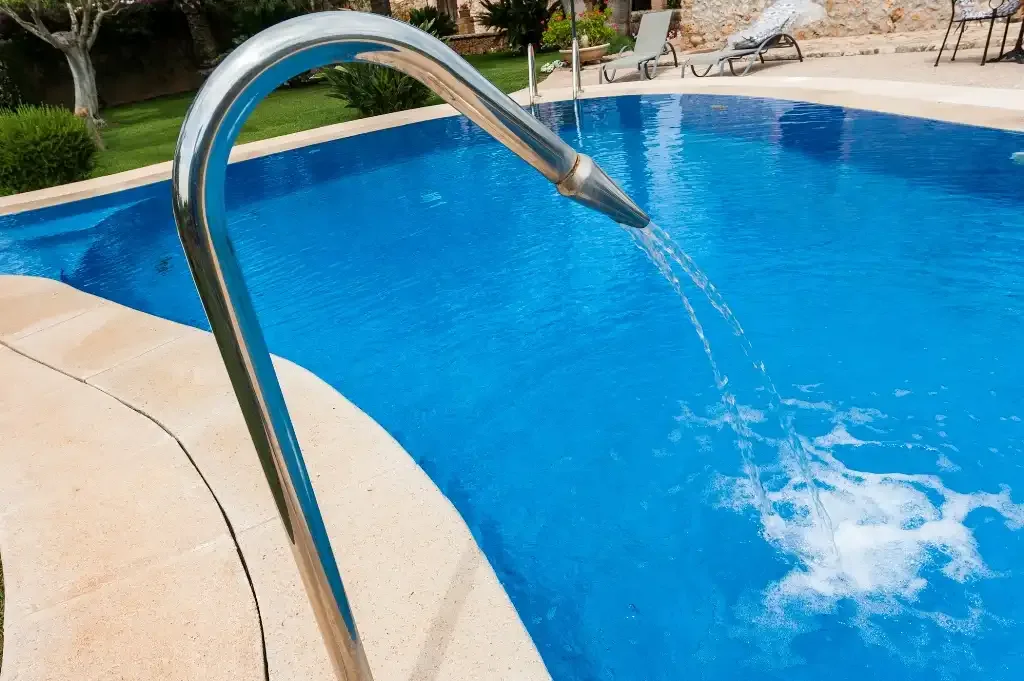 Una piscina con agua que fluye desde una boquilla metálica curva.
