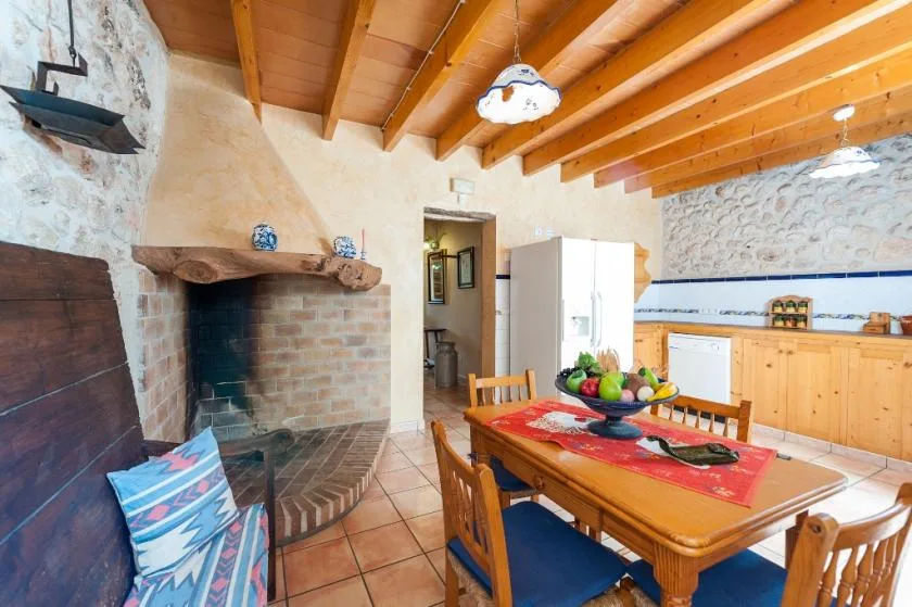Una cocina y comedor rústicos con una gran chimenea de ladrillo junto a la mesa.