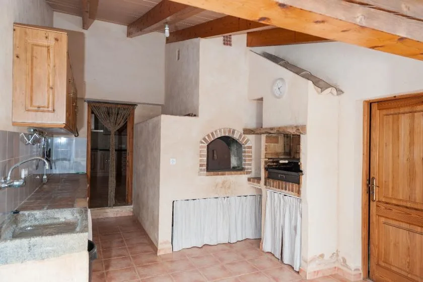 Una cocina y comedor rústicos con un horno de ladrillo y vigas de madera.
