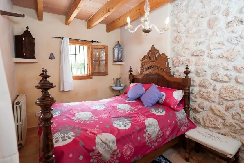 Un dormitorio con una cama de madera cubierta con ropa de cama rosa estampada.