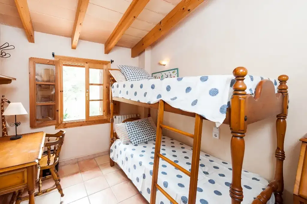 Un dormitorio con una litera de madera y una ventana.