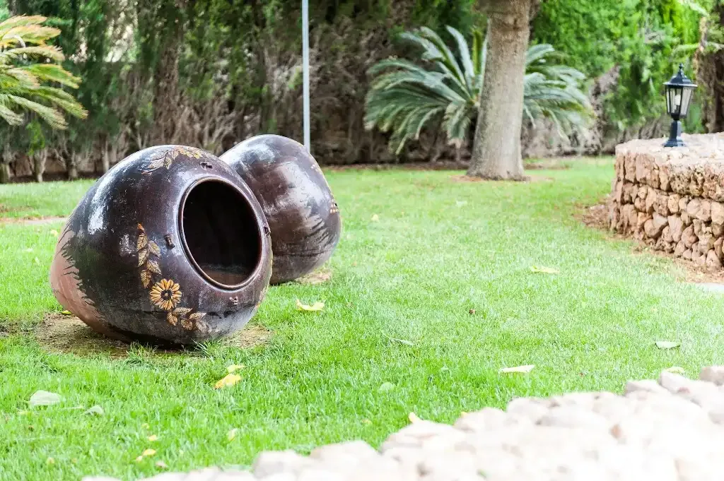 Un césped de jardín con dos grandes vasijas decorativas de cerámica.