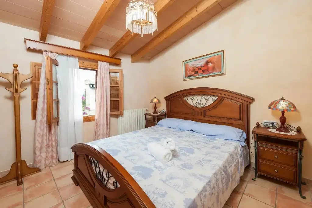 Dormitorio con una cama grande de madera y vigas de techo expuestas.