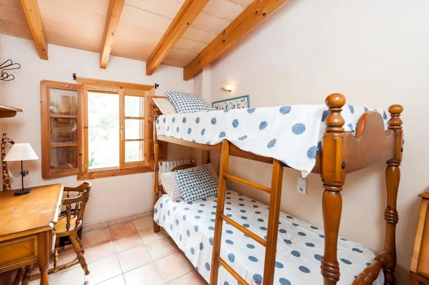 Una zona para dormir con literas, ropa de cama estampada en azul y una escalera de madera.
