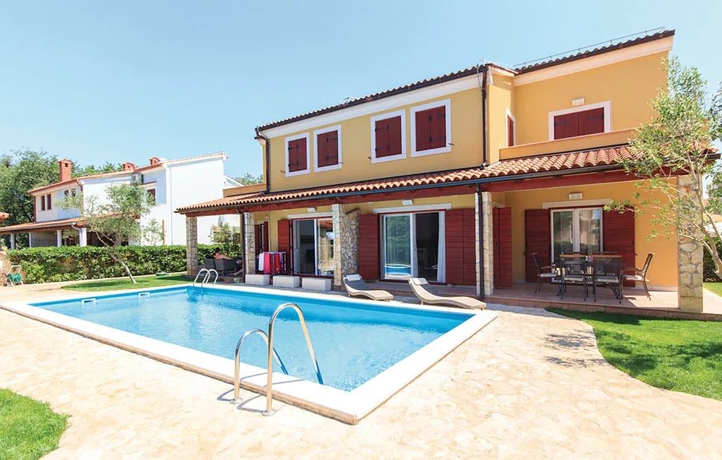 Una piscina está junto a una casa amarilla con un patio cubierto.