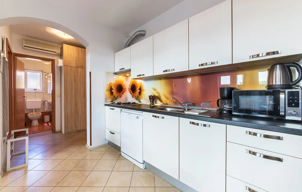 Una cocina luminosa con gabinetes blancos, una encimera y electrodomésticos.