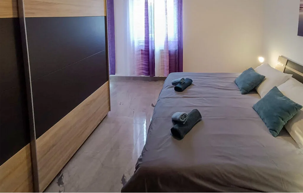 Dormitorio con una cama, toallas dobladas y cortinas en la ventana.