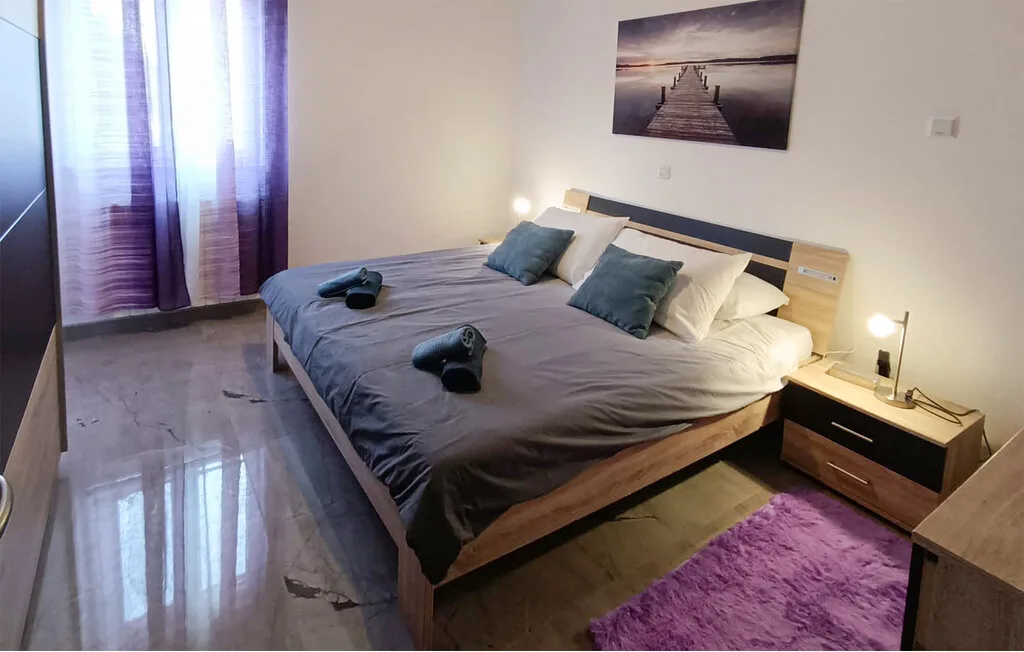 Un dormitorio con una cama grande, mesitas de noche y una alfombra morada.