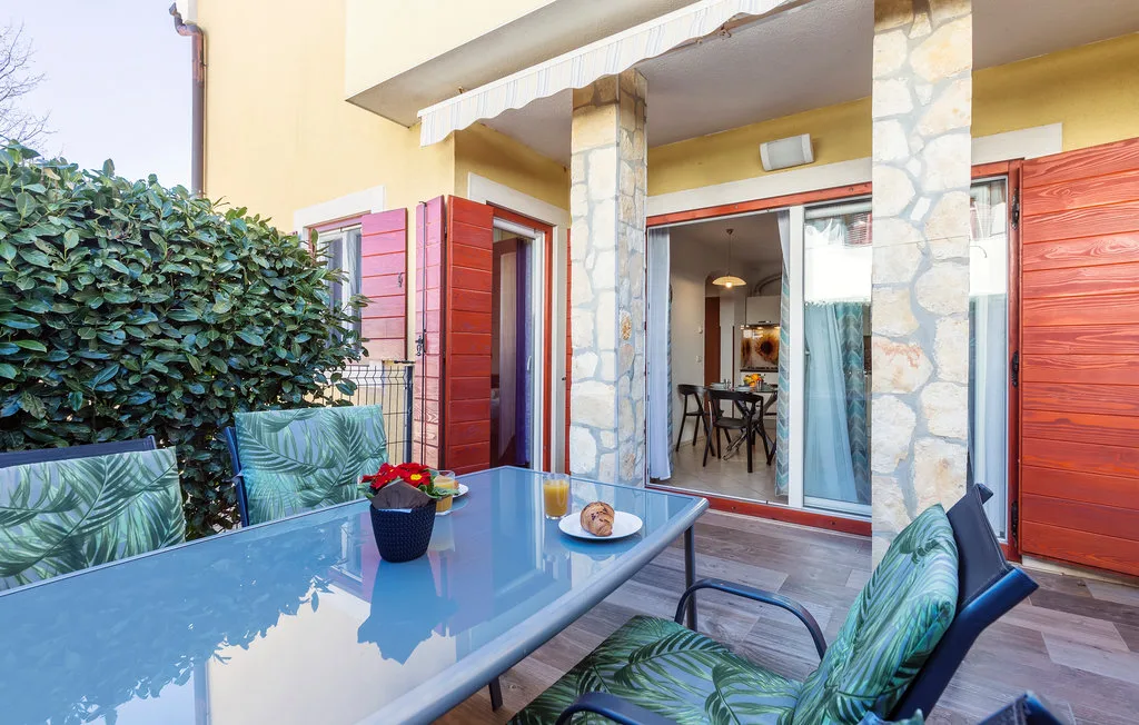 Un comedor en un patio exterior con una mesa de vidrio y asientos acolchados.