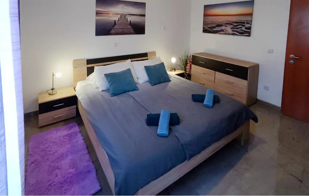 Un dormitorio con una cama bien tendida y muebles auxiliares a juego.
