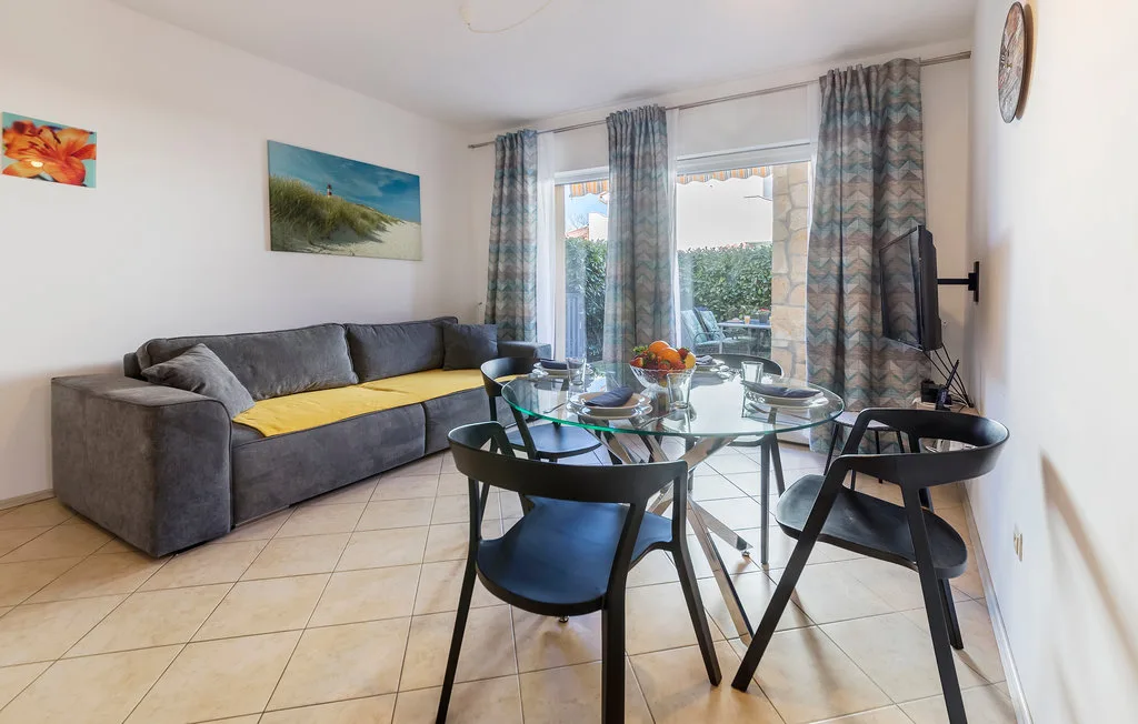 Sala de estar y comedor con un sofá gris y una mesa de comedor de vidrio.