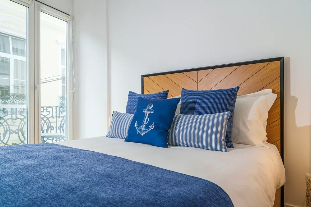 Dormitorio con una cama bien tendida y cojines decorativos azules.