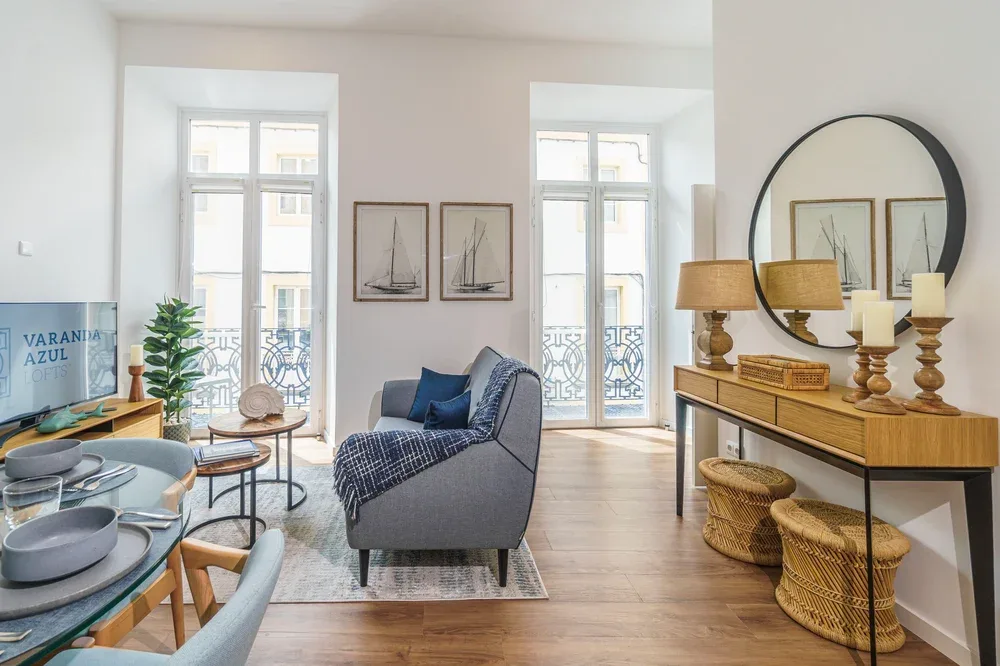 A bright living room with seating, a dining area, and tall windows.