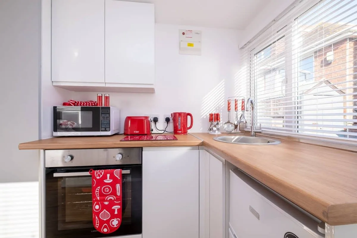 Una cocina luminosa con encimeras de madera, microondas y fregadero junto a la ventana.