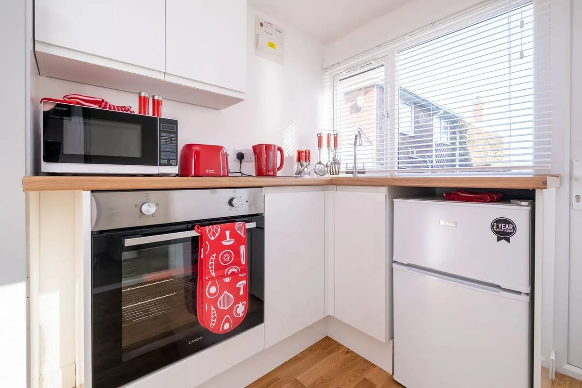 Una cocina compacta con gabinetes blancos, una encimera y una ventana amplia.