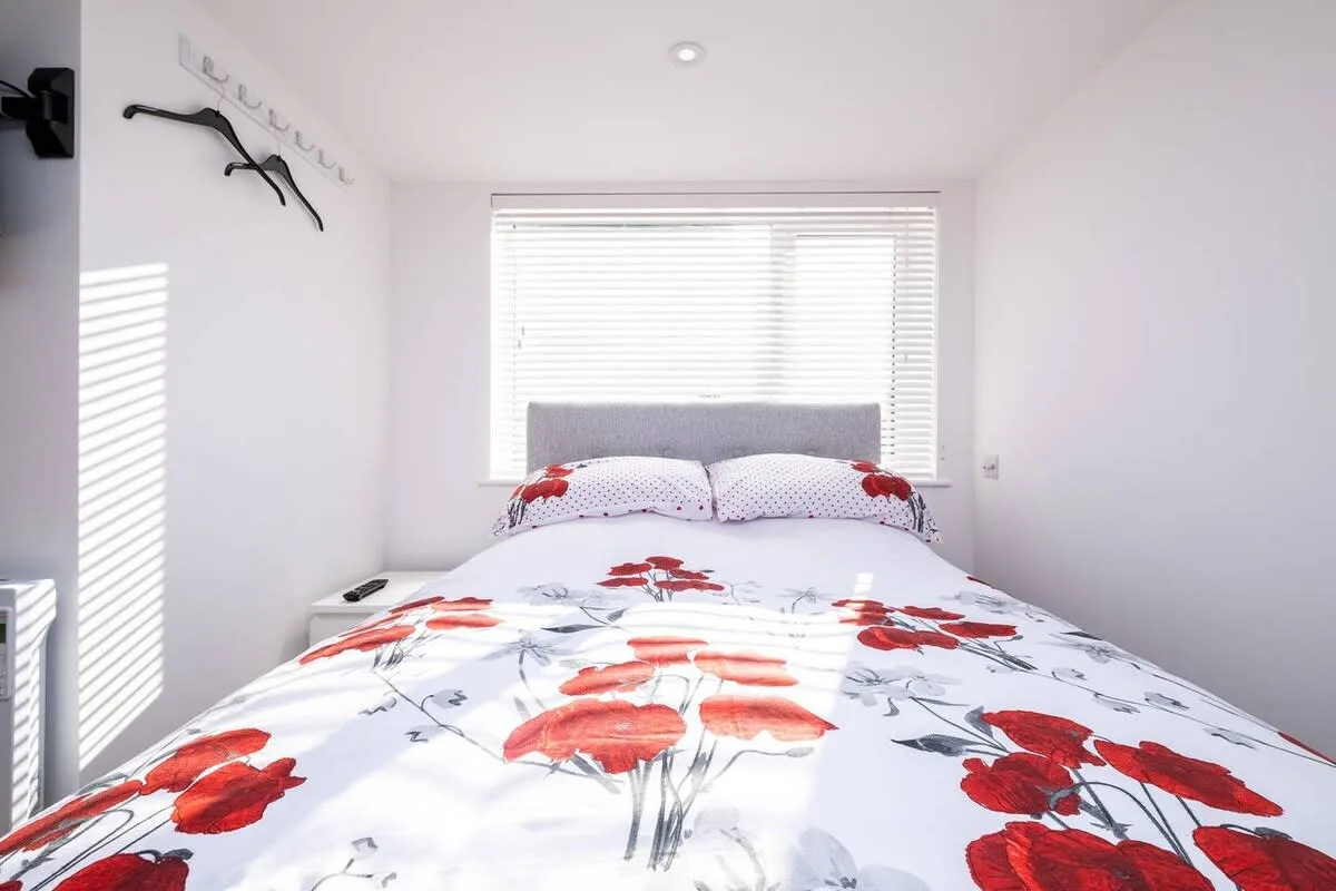 Un dormitorio luminoso con ropa de cama floral y una ventana con persianas.