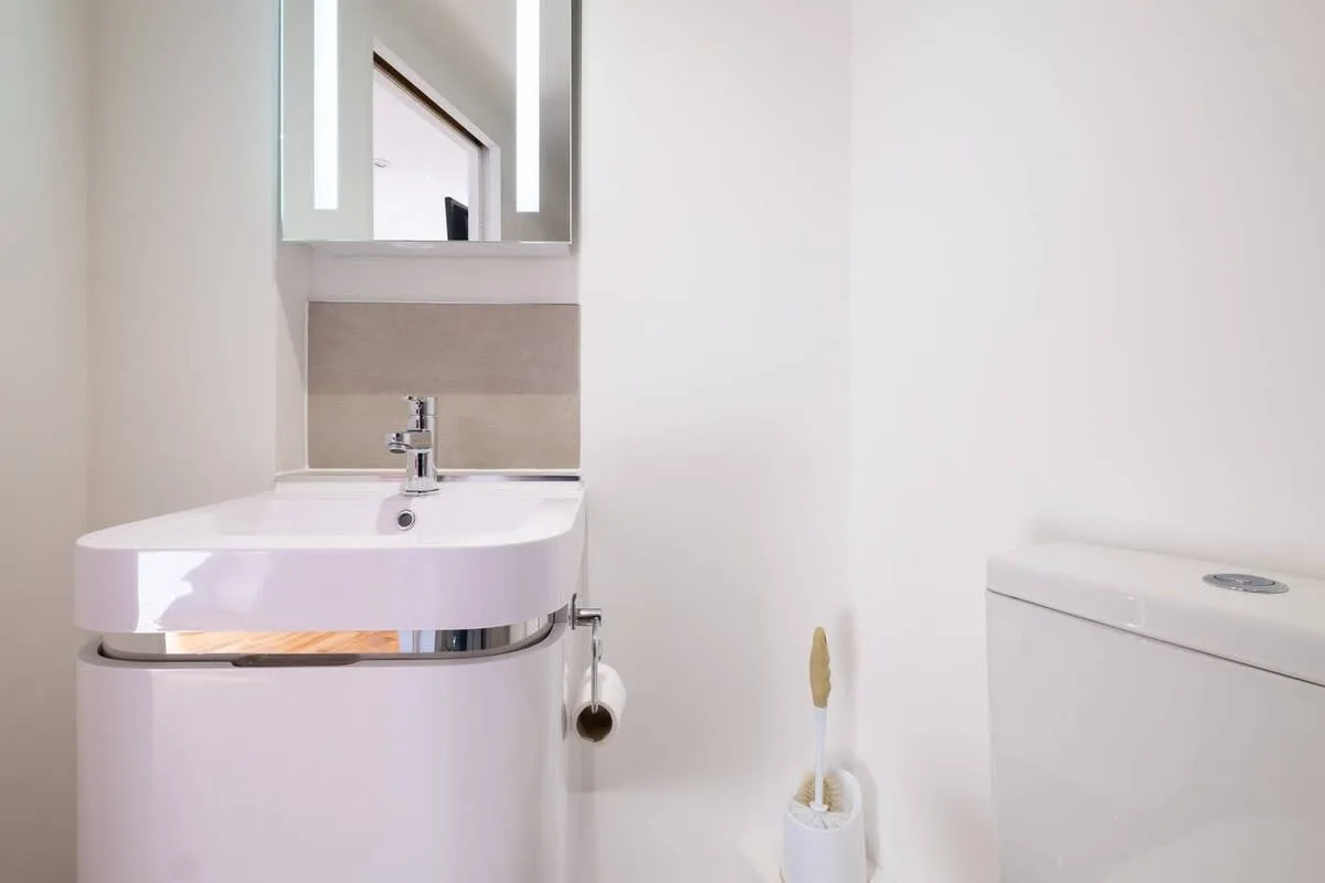 Un baño con lavabo, espejo e inodoro.