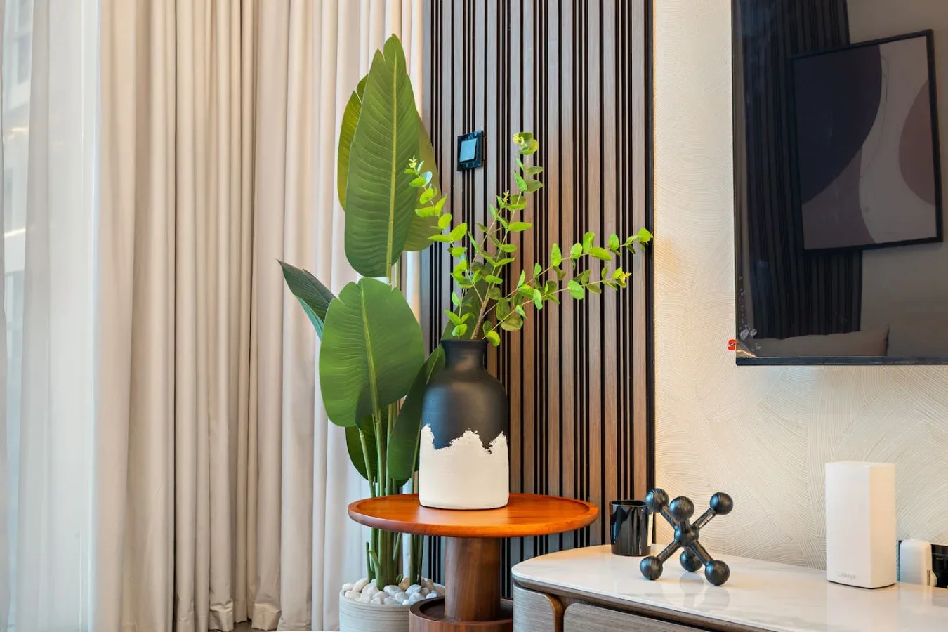 A living room corner with a plant and decorative vase beside a television.