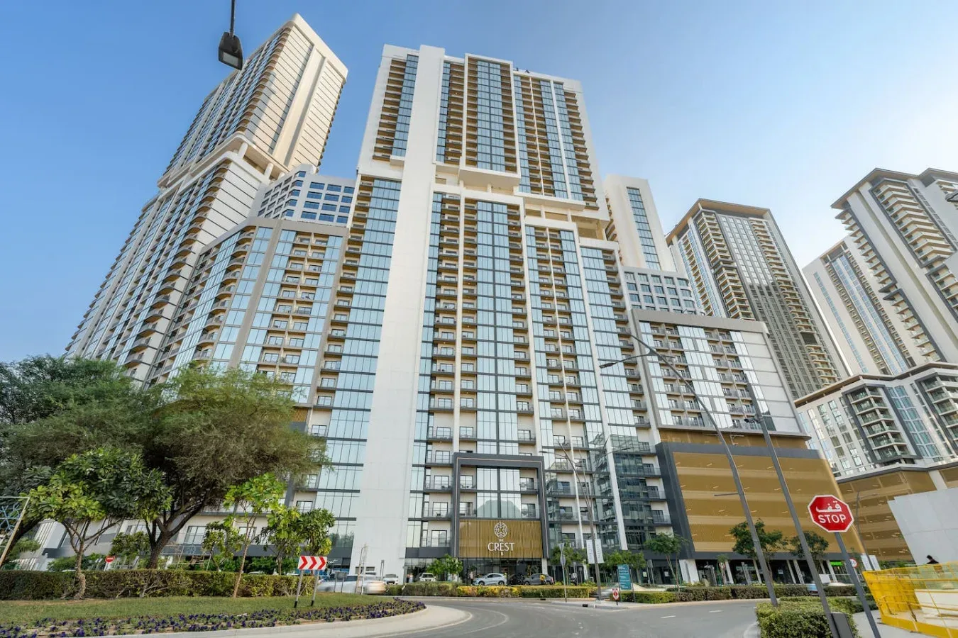A cluster of modern high-rise buildings stands beside a landscaped road.