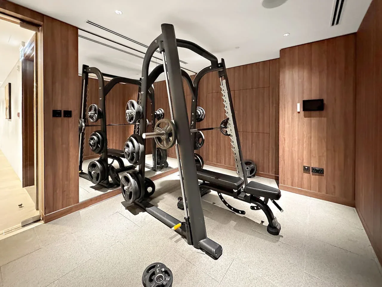 A compact gym with a weight-training machine and exercise weights.