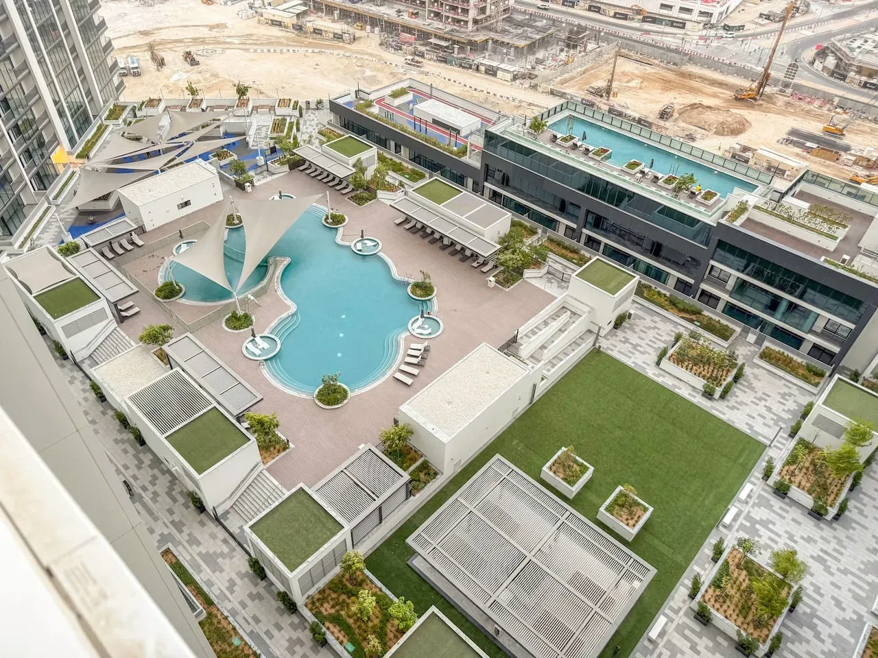 An aerial view of a rooftop pool deck with landscaped seating areas.