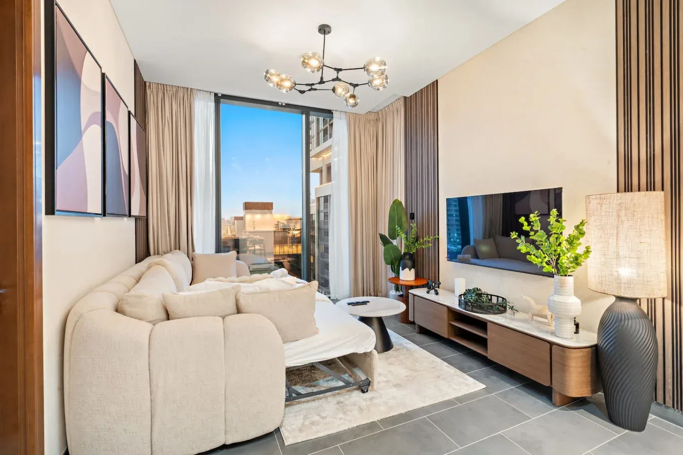 A bright living room with seating, a television, and large windows.