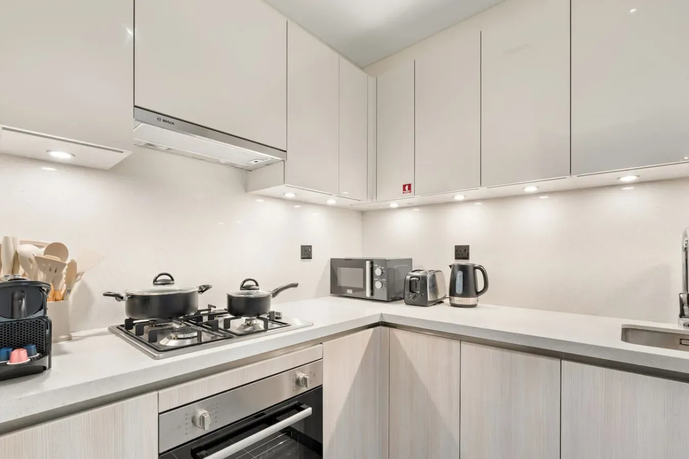 A bright modern kitchen with white cabinets and a gas cooktop.