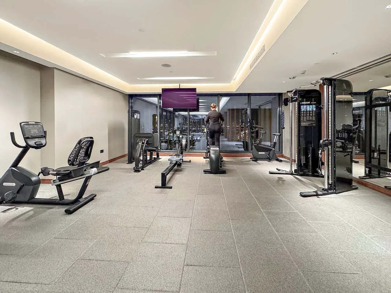 A gym with exercise equipment and a person using a treadmill.