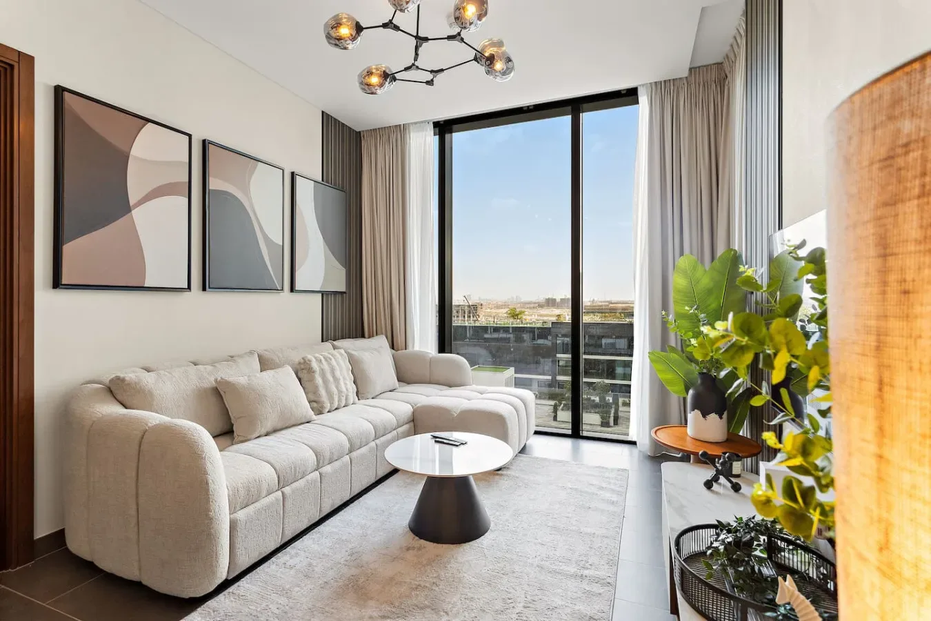 A bright living room with seating, abstract wall art, and large windows.
