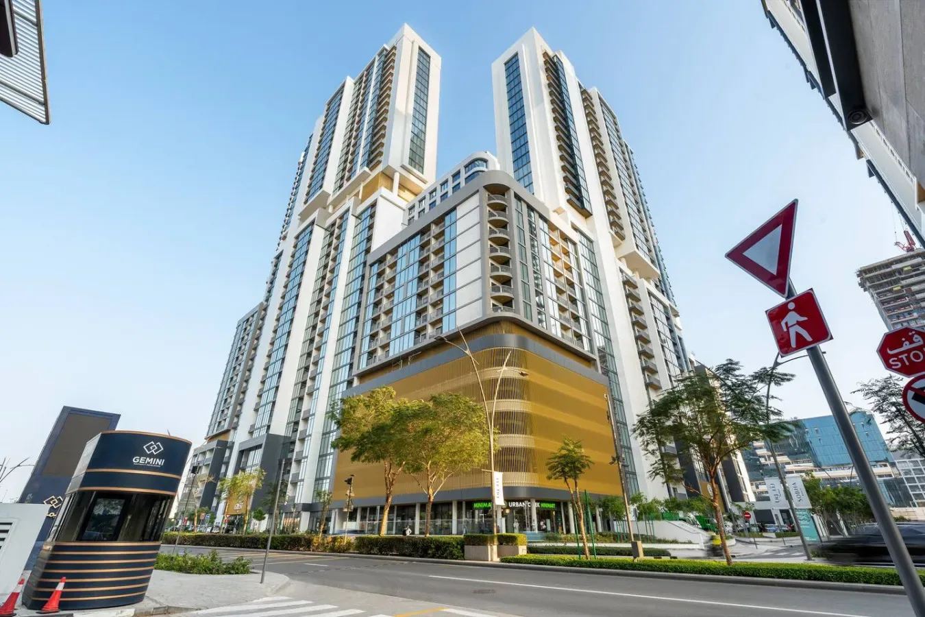 Un edificio moderno y alto se alza junto a una calle urbana.