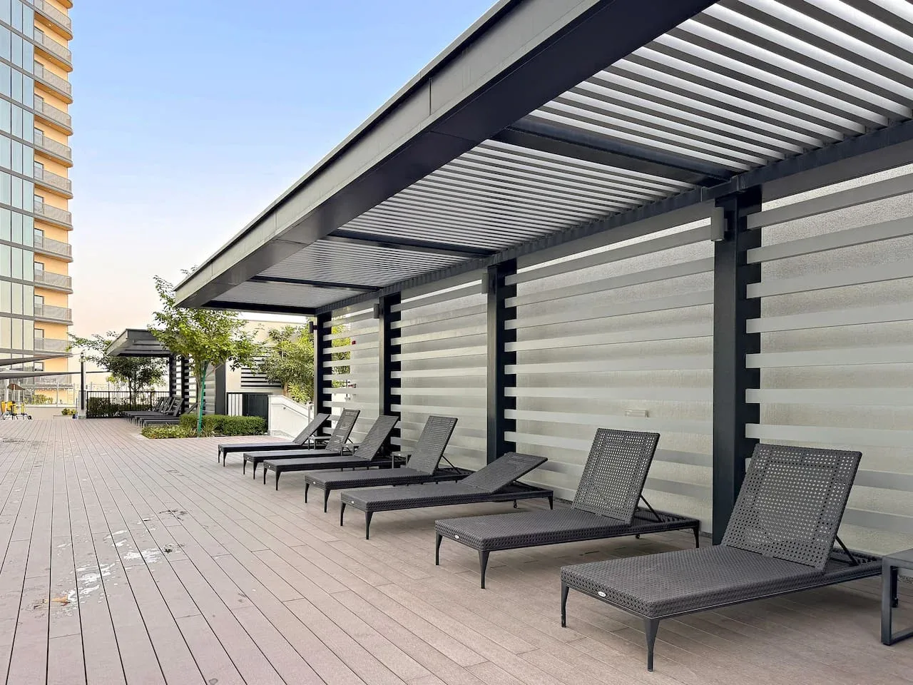 A rooftop deck has lounge seating beneath a slatted shade canopy.