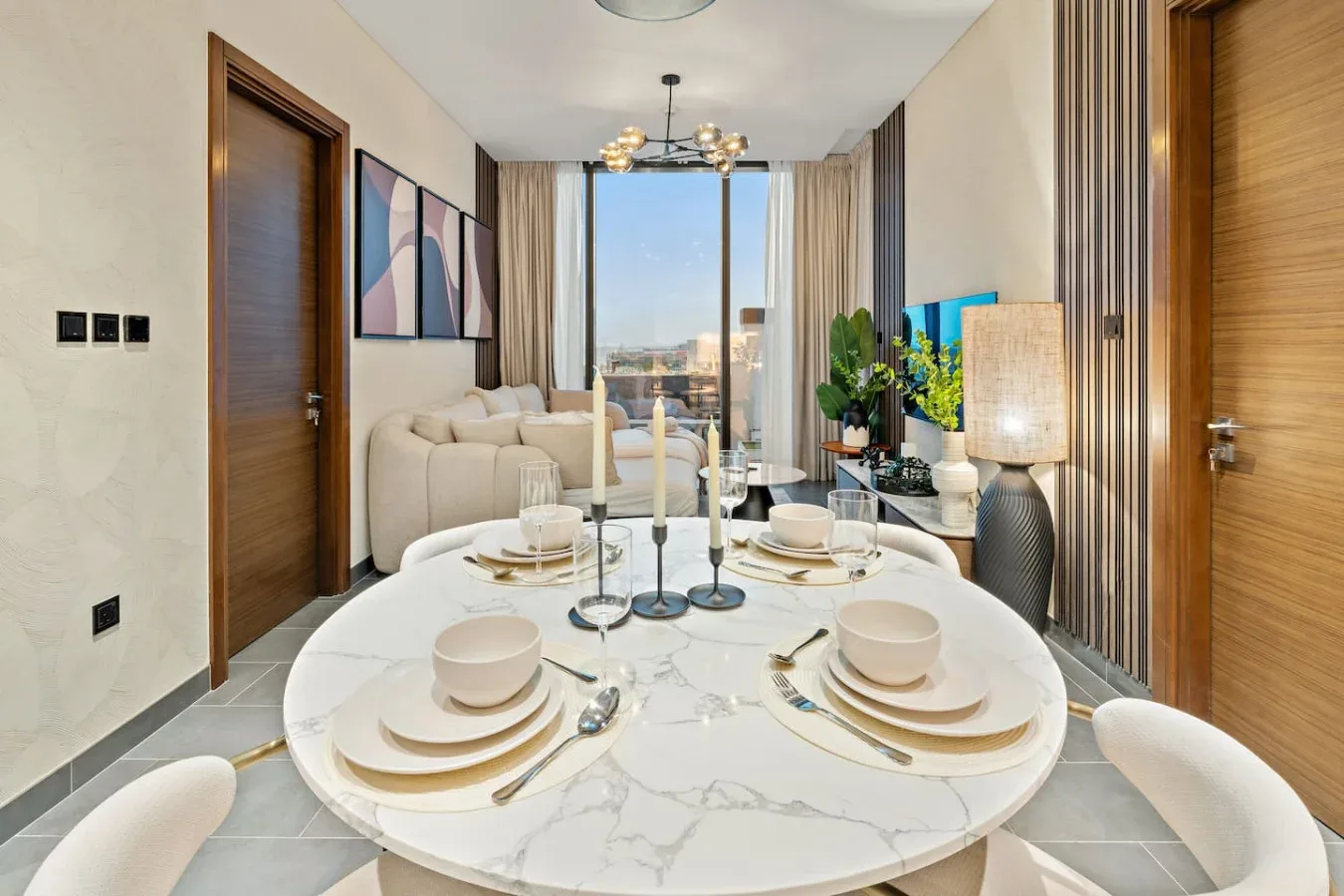 A living room with a round dining table set with dishes in the foreground.