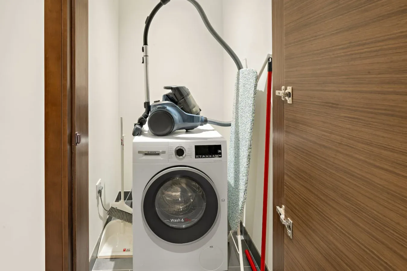 A laundry nook with a front-loading washing machine and cleaning equipment.
