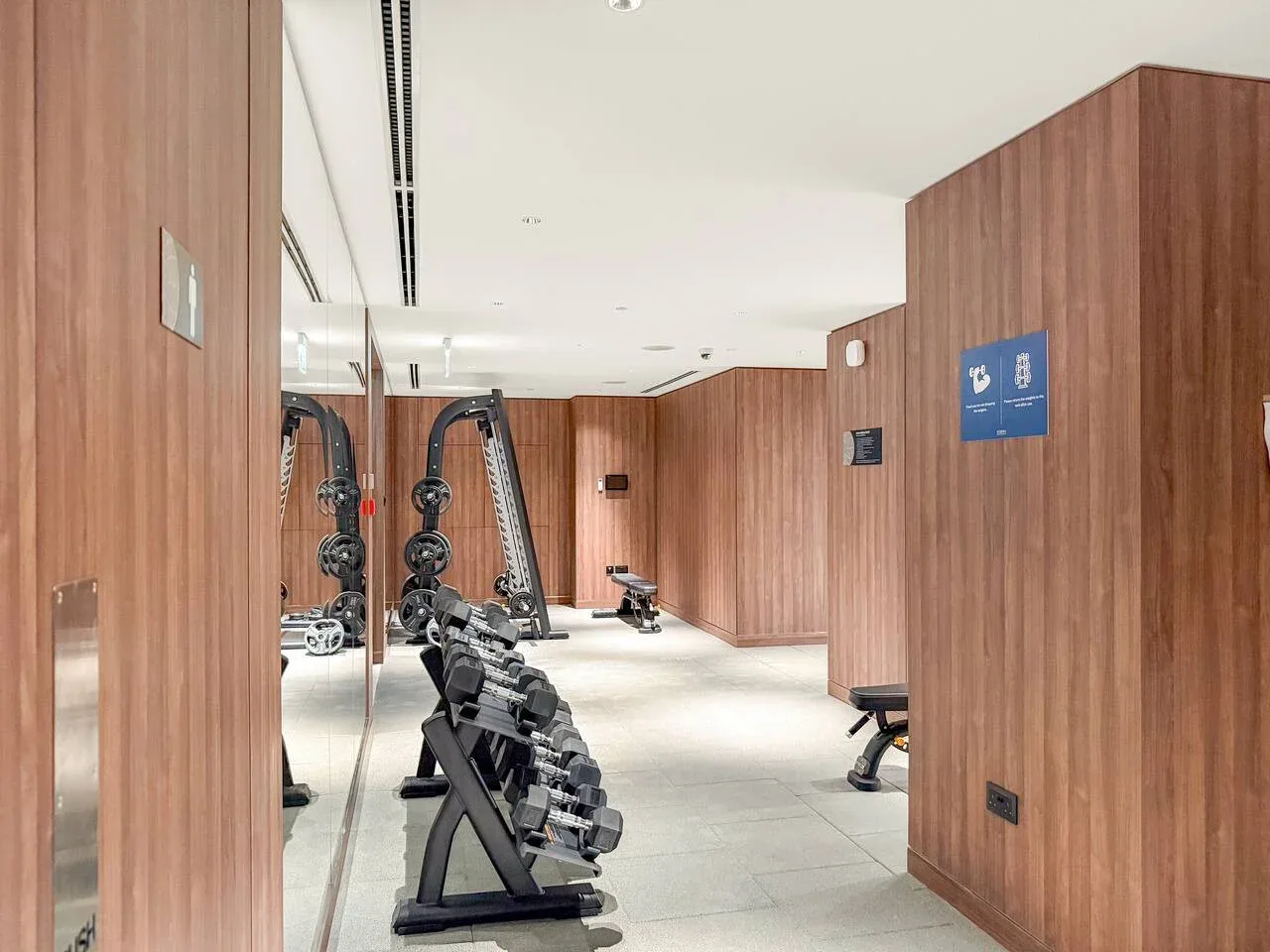 A gym with weight racks and exercise equipment along wood-paneled walls.