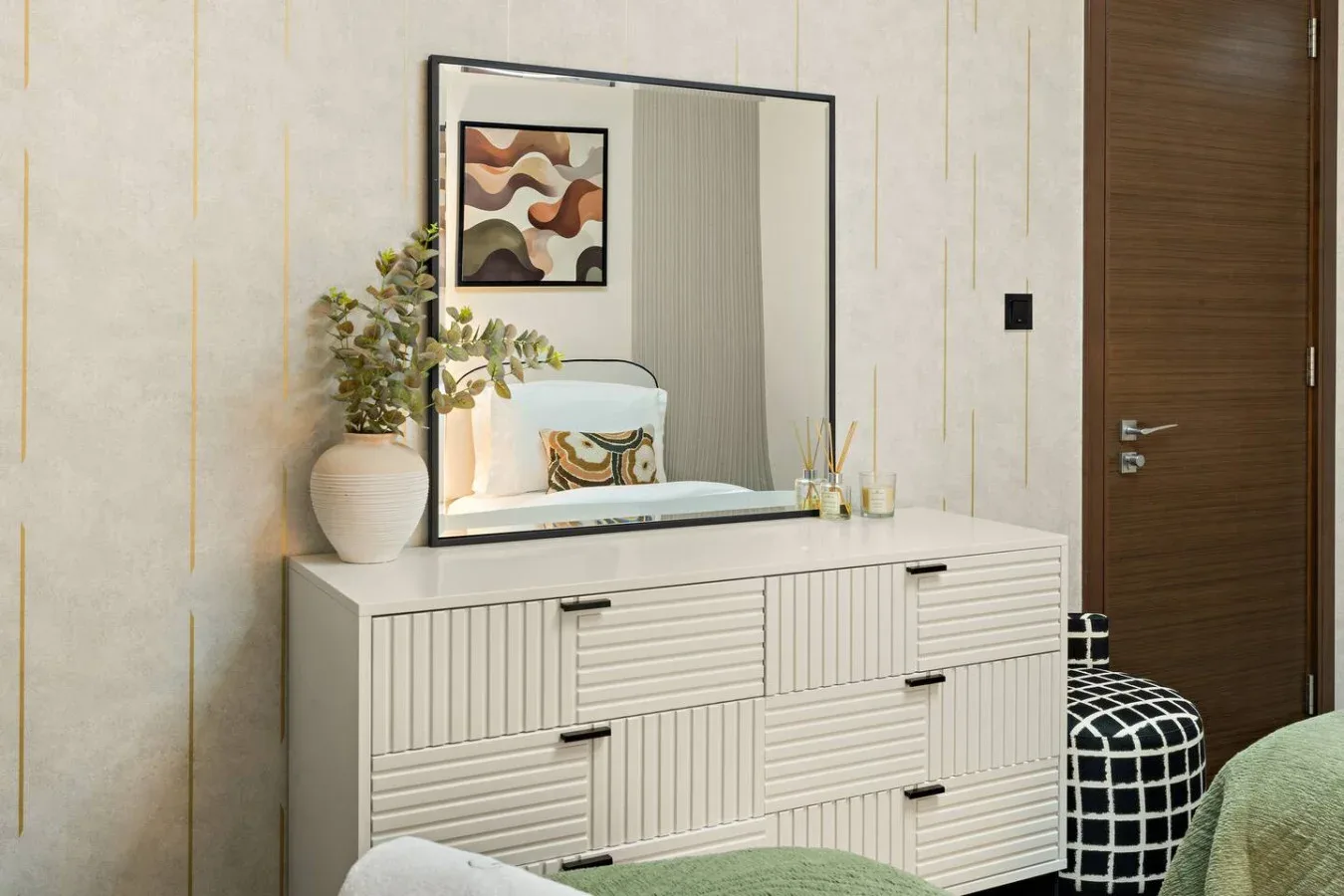 A bedroom dresser with a mirror, decorative objects, and a wooden door.