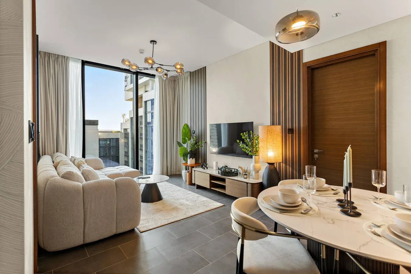 A modern living and dining area with seating, a television, and a set dining table.