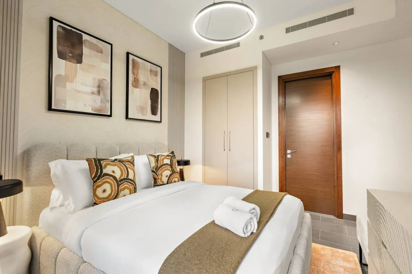 A bedroom with a neatly made bed and framed artwork on the wall.