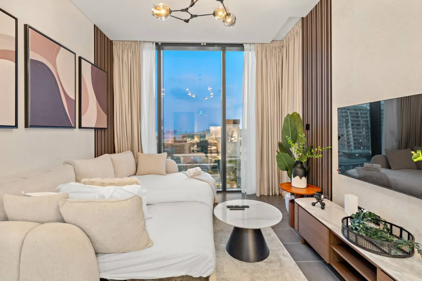 A bright living room with pale seating, a coffee table, and large windows.