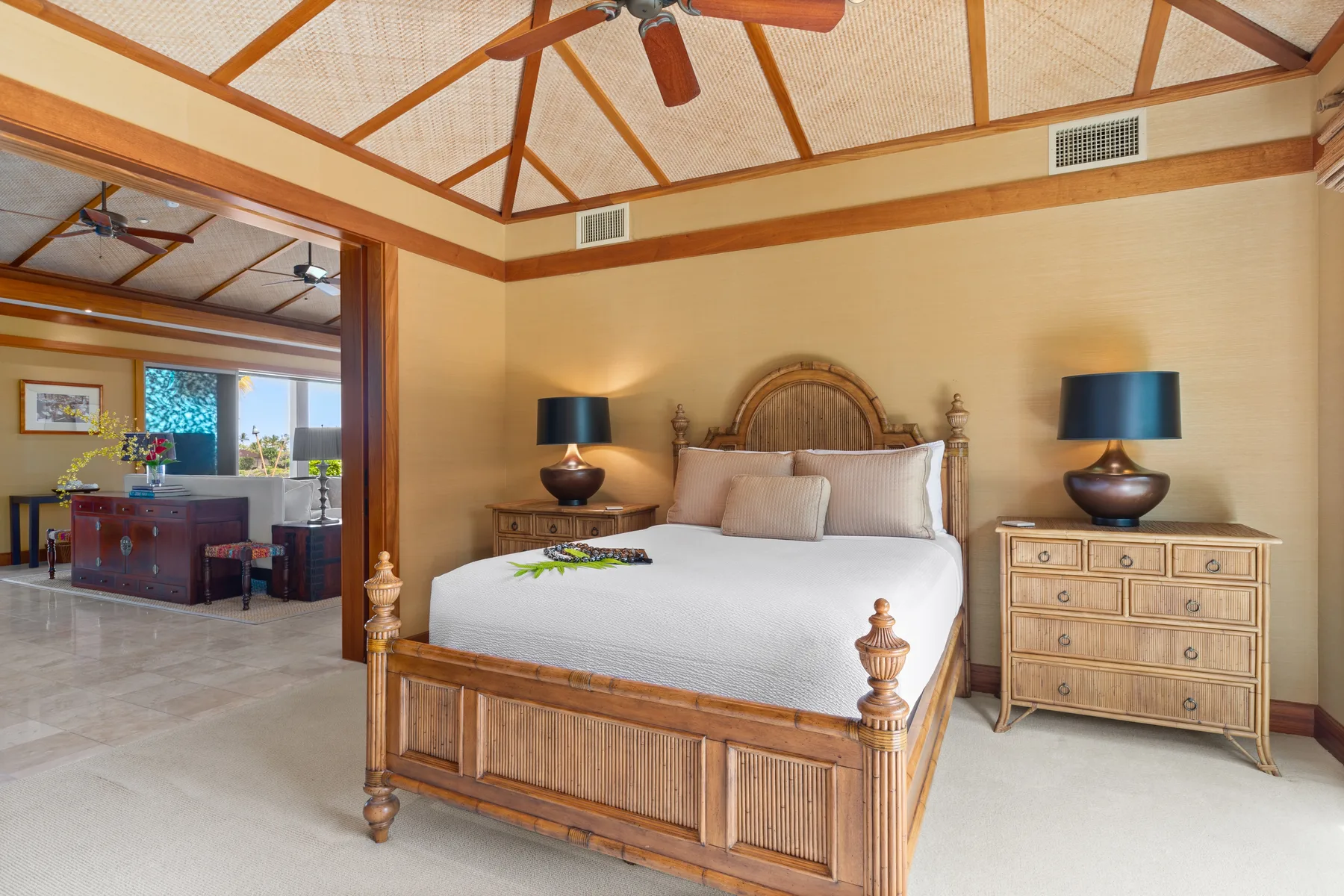A bedroom with a wooden bed, matching bedside lamps, and a high beamed ceiling.