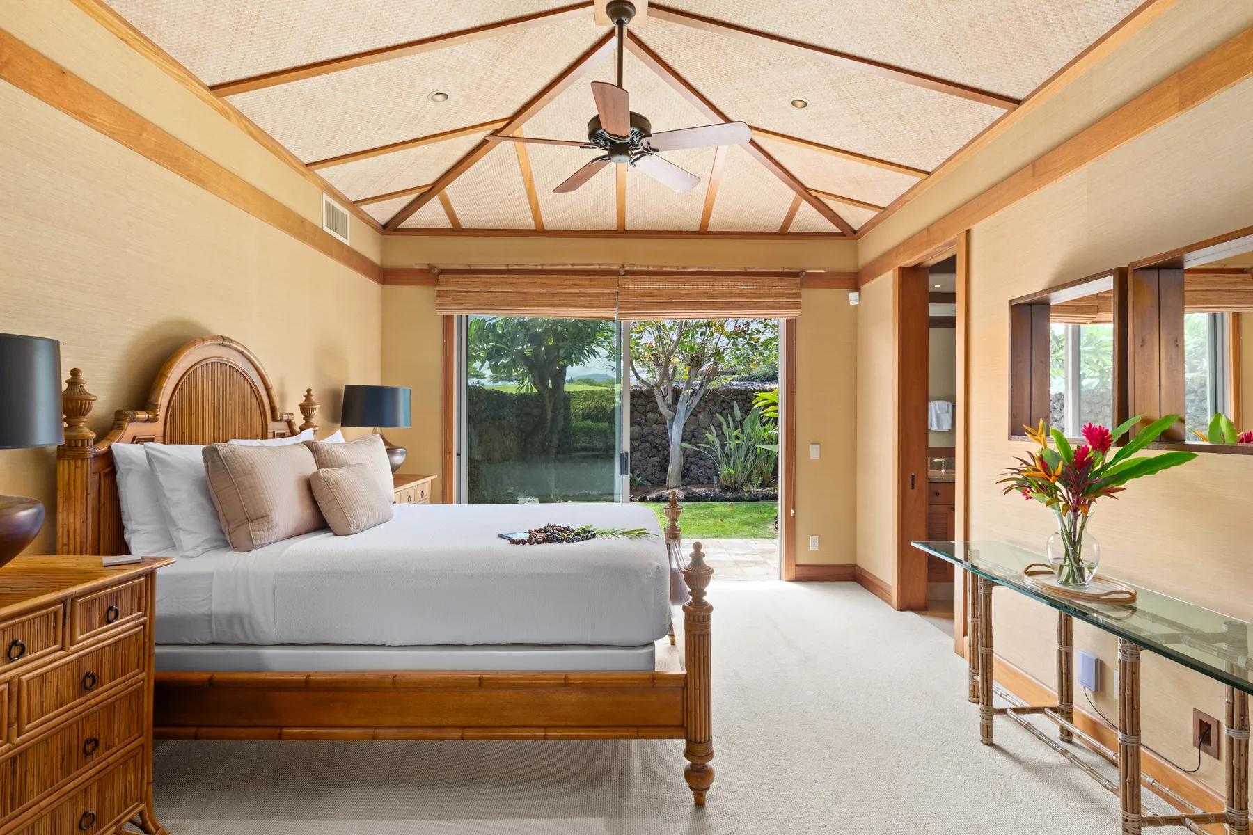 A bedroom with a large bed and sliding glass doors opening onto a garden.
