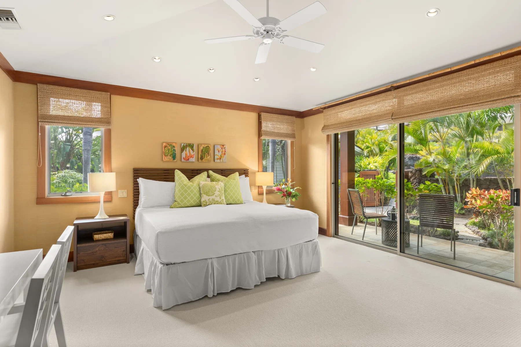 A bedroom with a made bed, bedside tables, and glass doors opening onto a garden.