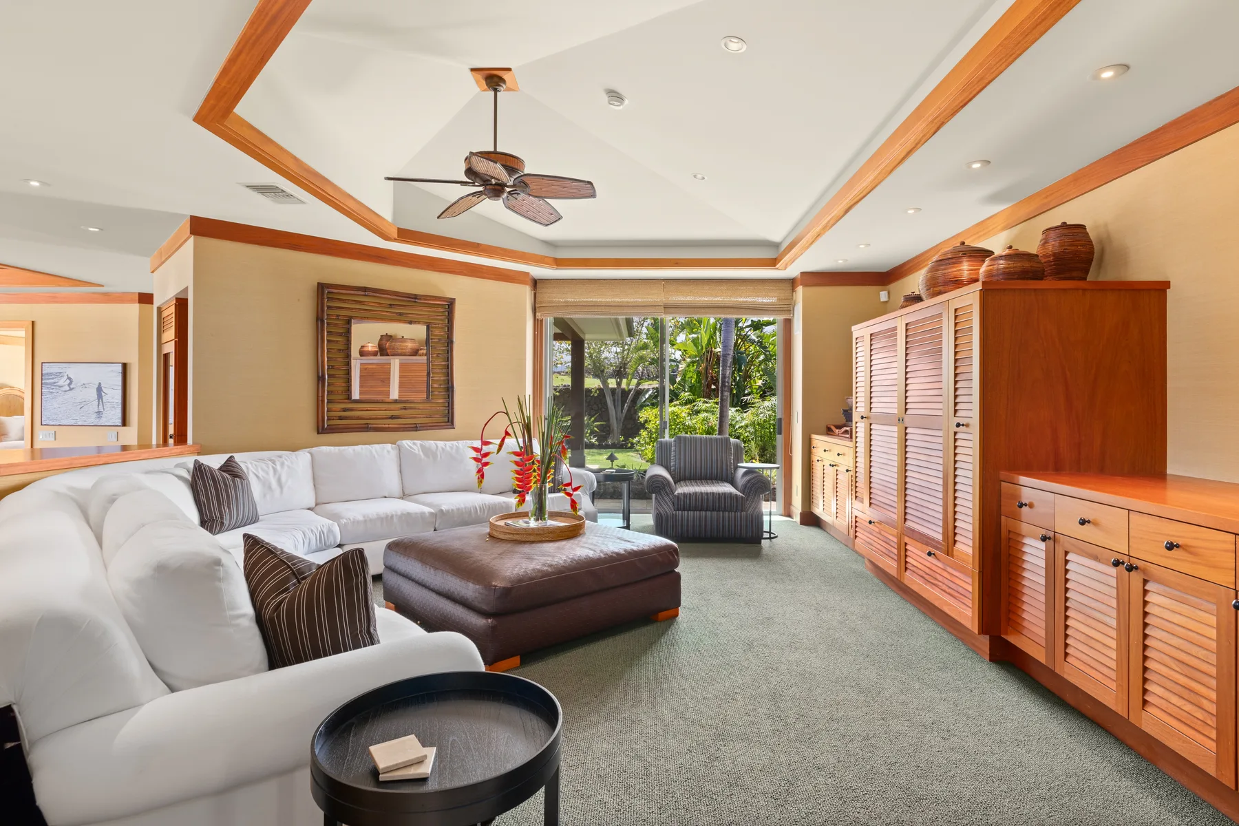 A living room with seating arranged around a coffee table beside large windows.