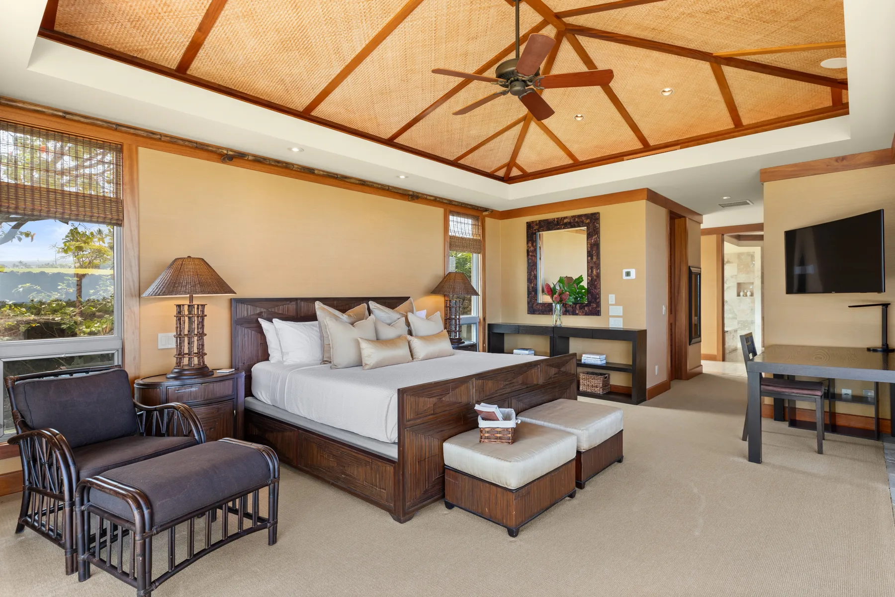 A bedroom with a large bed, lounge chairs, and a television.