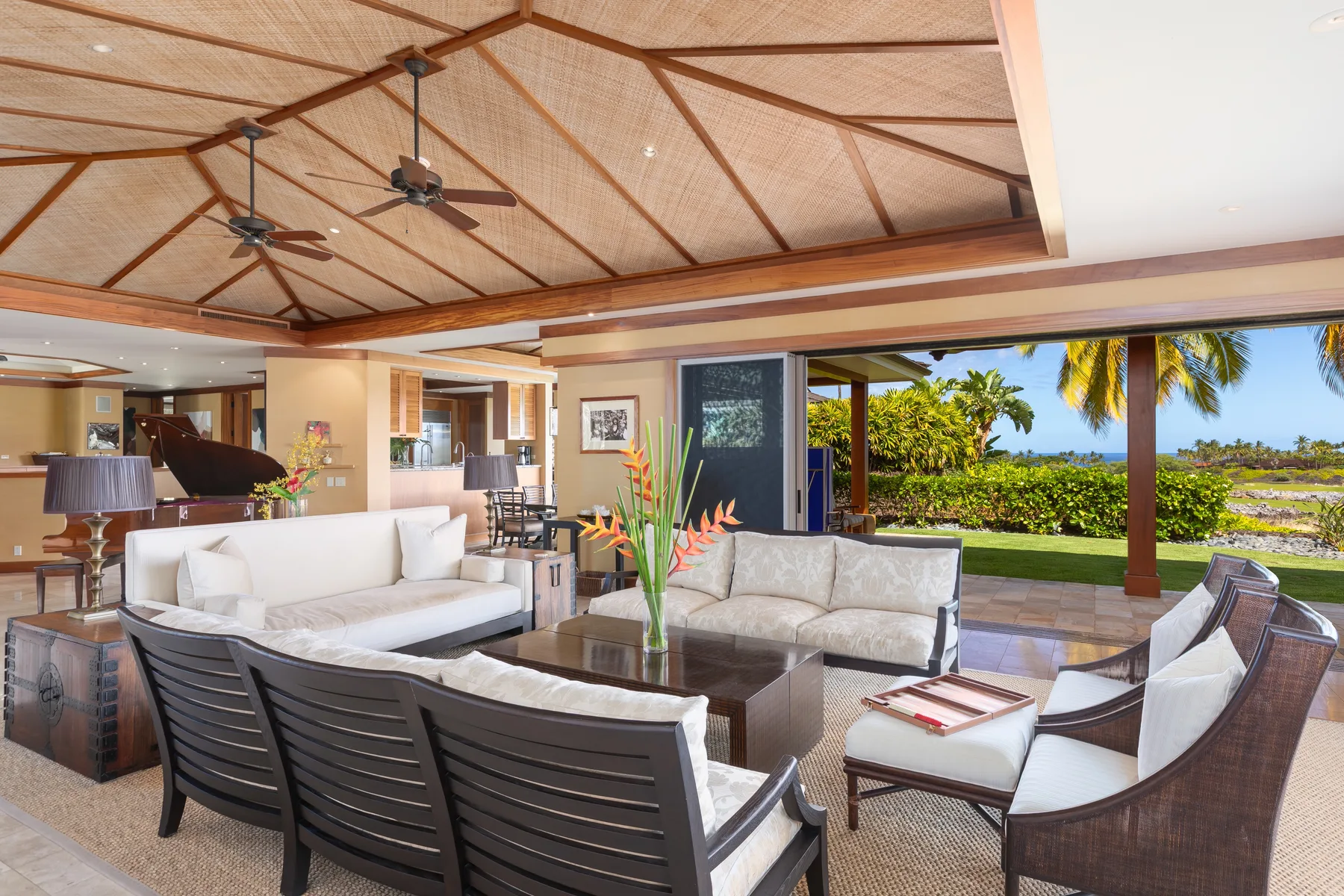 An open living room with seating and a wide view of the tropical garden.