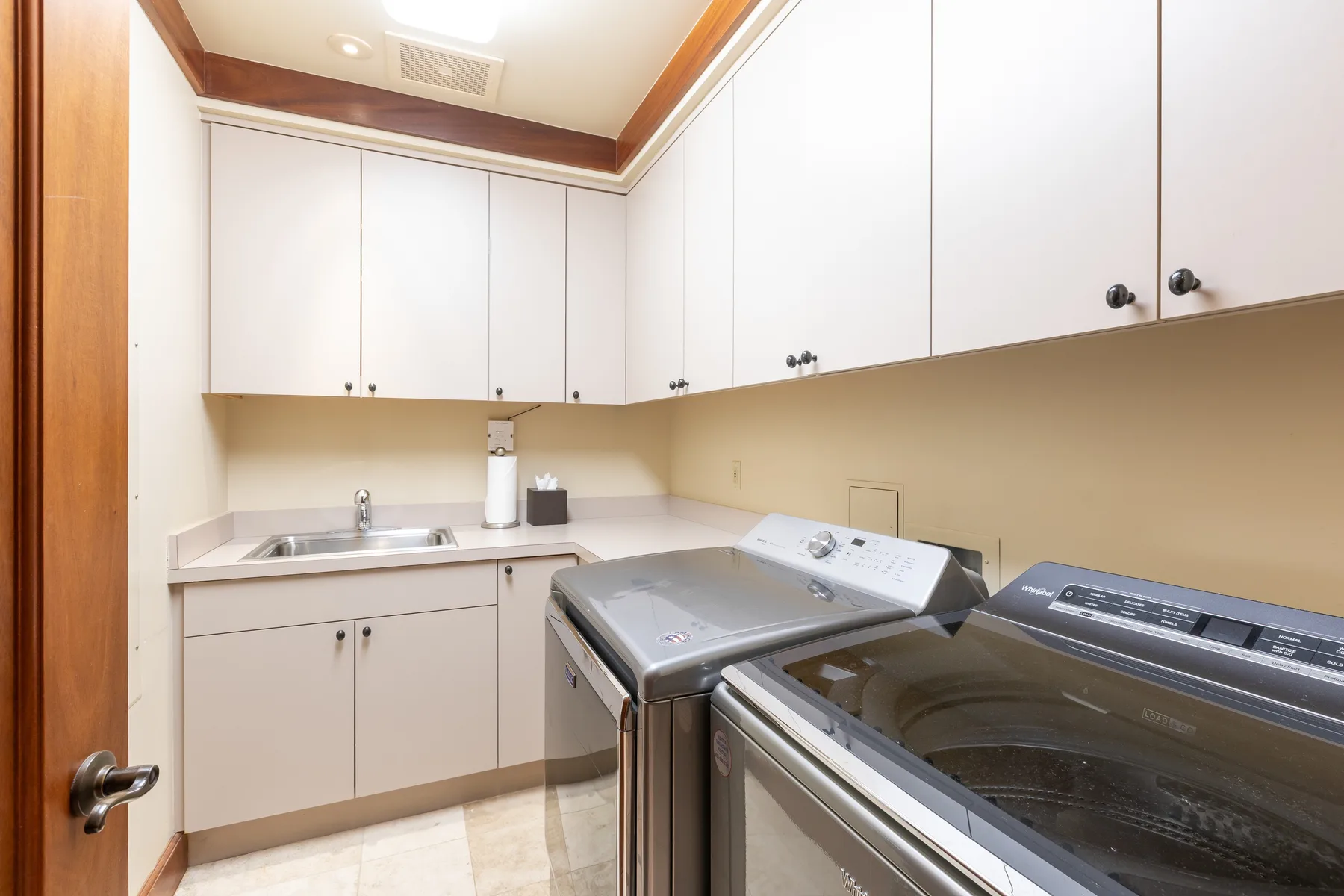 A laundry room with a countertop, sink, and washing machines.