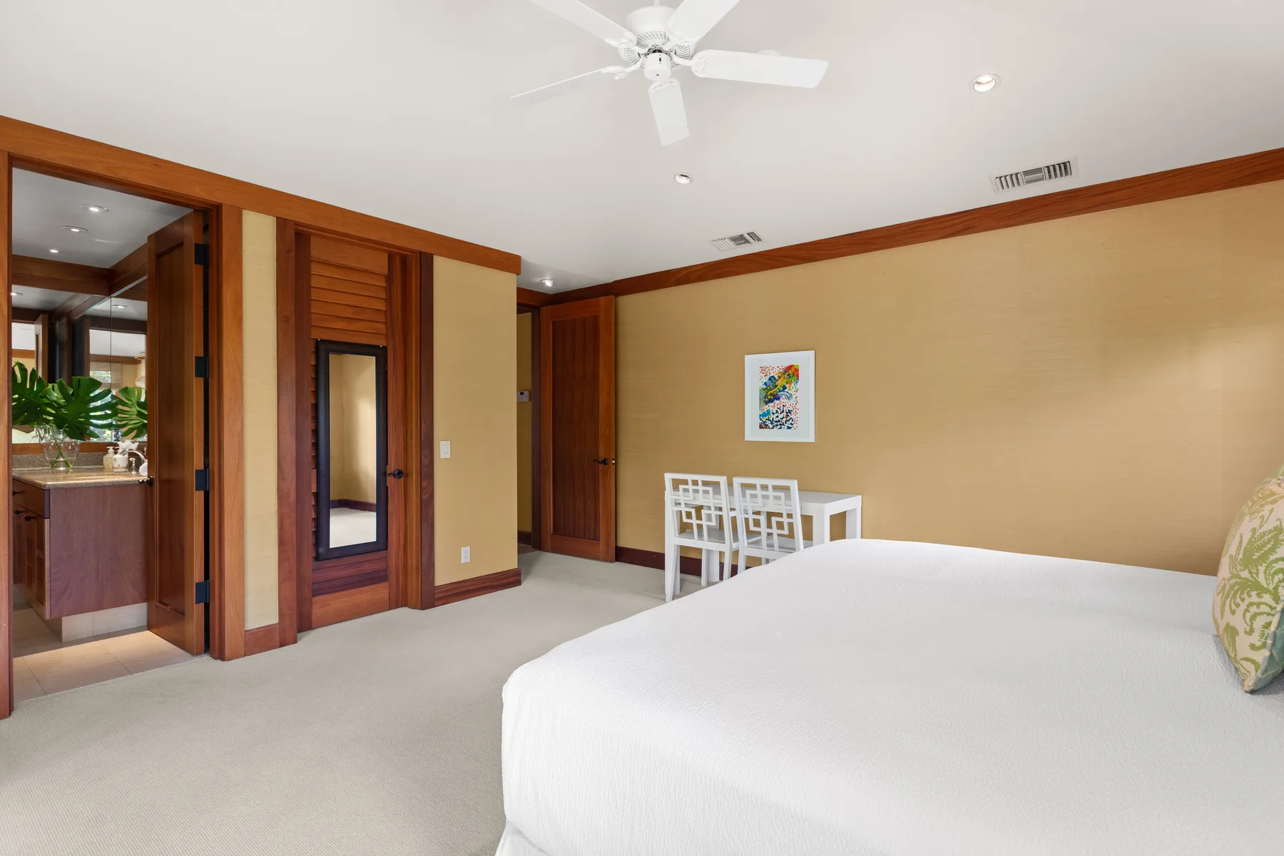 A bedroom with a large bed, a small dining table, and warm wood trim.