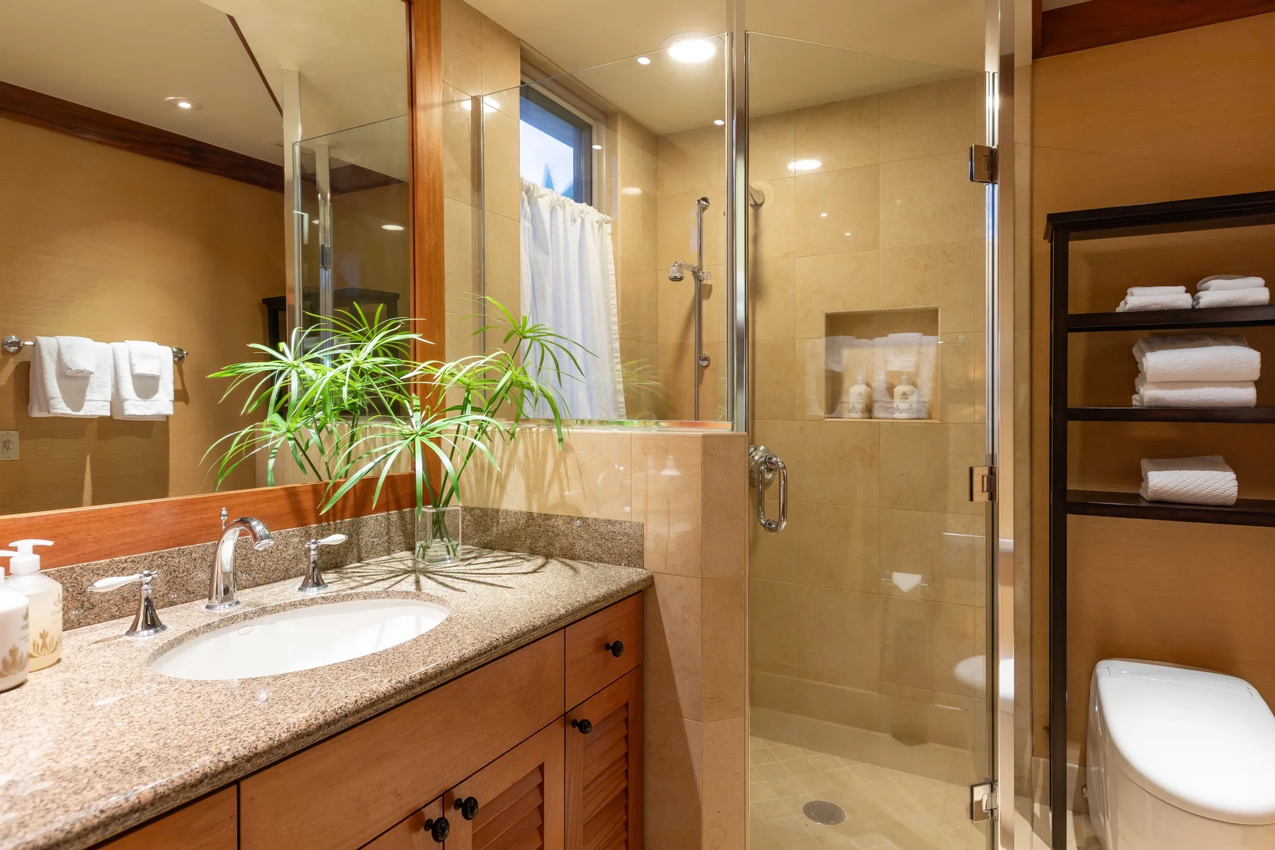 A bathroom with a vanity, mirror, and glass-enclosed shower.