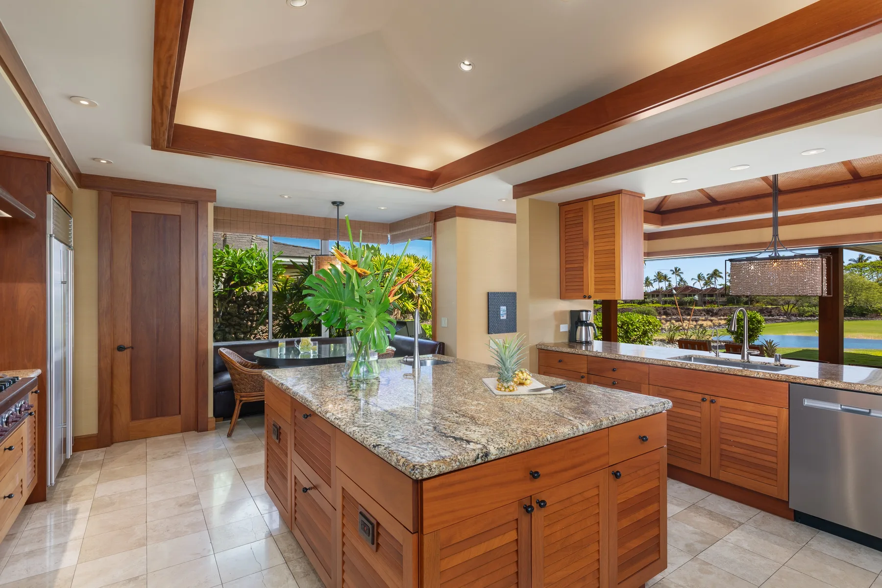 A spacious kitchen with a central island and wide windows overlooking greenery.